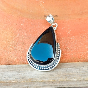 May include: A black gemstone pendant with a silver setting. The pendant is shaped like a teardrop and has a beaded border.