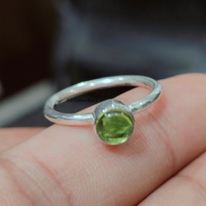 May include: A silver ring with a green gemstone. The ring is simple and elegant, and the gemstone is a beautiful shade of green.