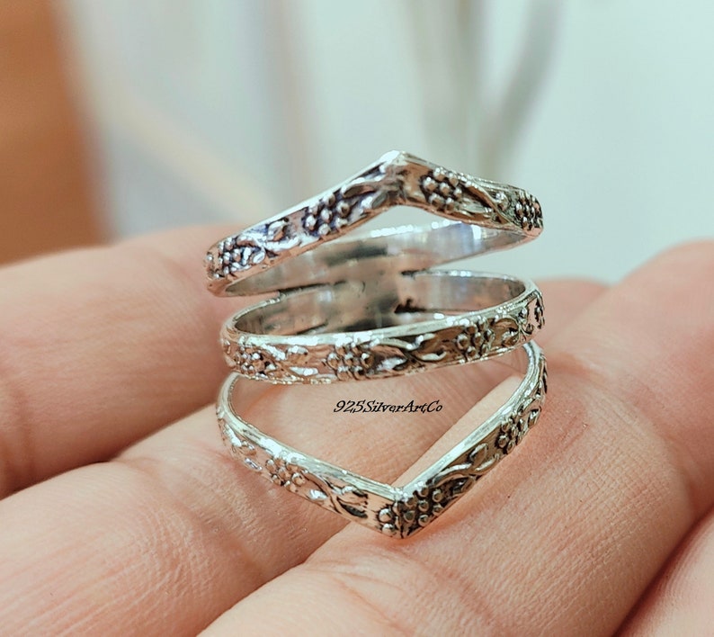 Op de afbeelding: Zilveren ring met een bloemenmotief. De ring is gemaakt van drie banden die met elkaar zijn verweven. De banden zijn allemaal versierd met een bloemenpatroon. De ring is maat 7.