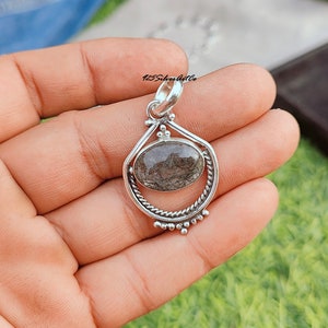 May include: Silver pendant with a clear quartz stone with black inclusions. The pendant is in the shape of a teardrop with a twisted silver bail.
