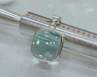 May include: A silver pendant with a light blue aquamarine gemstone. The pendant is square shaped and has a smooth, polished finish. The gemstone is set in a silver bezel.