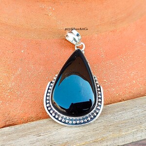 May include: A black onyx pendant with a silver teardrop setting and a beaded border. 925SilverArtCo is printed on the bail.