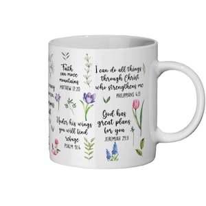 Op de afbeelding: Witte keramische mok met bloemenillustraties en Bijbelcitaten. De mok bevat zinnen als 'Geloof kan bergen verzetten' en 'Ik kan alle dingen doen door Christus'. Het ontwerp bevat verschillende bloemen en groen.