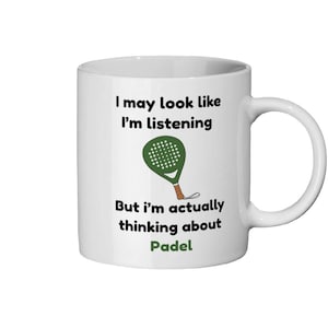 May include: White ceramic mug with a black handle. The mug features the text "I may look like I'm listening, But I'm actually thinking about Padel" along with a green padel racket graphic.