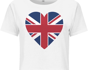 Puede incluir: Top corto blanco con un diseño en forma de corazón de la bandera del Reino Unido, la Union Jack. El corazón es rojo, blanco y azul. La camiseta tiene mangas cortas y cuello redondo.
