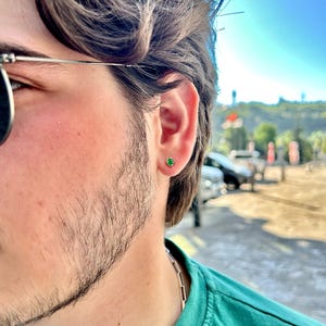 A 925 sterling silver men’s stud earring with a deep green stone, shown in close-up against a dark background. Minimalist and stylish, ideal for men’s everyday jewelry.