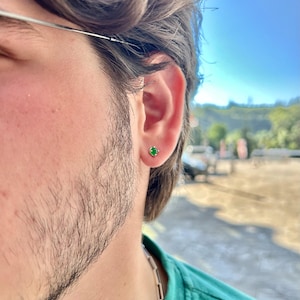 A 925 sterling silver men’s stud earring with a deep green stone, shown in close-up against a dark background. Minimalist and stylish, ideal for men’s everyday jewelry.