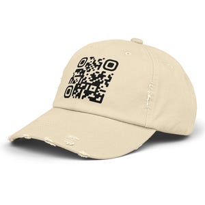 May include: A distressed, cream-colored baseball cap featuring a black QR code on the front. The cap has a curved brim and a slightly worn appearance, with distressed edges. The hat is a casual accessory.