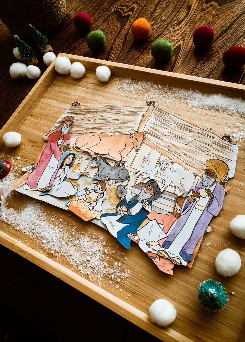 May include: A handcrafted Nativity scene illustration featuring Mary, Joseph, baby Jesus, and the Three Wise Men. The scene is set in a wooden tray with decorative snow and colourful felt balls.