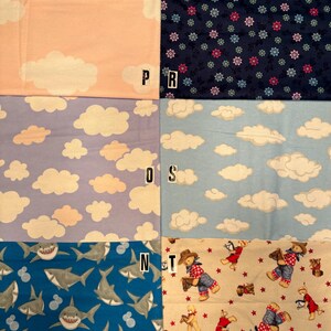 Op de afbeelding: Een collectie van zes stoffen stalen met verschillende patronen: perzik met witte wolken, donkerblauw met kleine bloemmotieven, lichtpaars met witte wolken, lichtblauw met witte wolken, blauw met grijze haaien en beige met teddyberen.