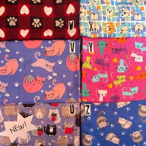 Op de afbeelding: Zes stoffen met verschillende kattenpatronen. Links boven een rood en zwart ruitpatroon met witte harten en pootafdrukken gelabeld W. Rechts boven een blauw en wit raster met kattengezichten gelabeld X. Midden links paars met roze katten gelabeld V. Midden rechts roze met kleurrijke katten gelabeld Y. Links onder lichtpaars met katten die aardbeien vasthouden gelabeld U en NEW. Rechts onder blauw met slapende katten gelabeld Z.