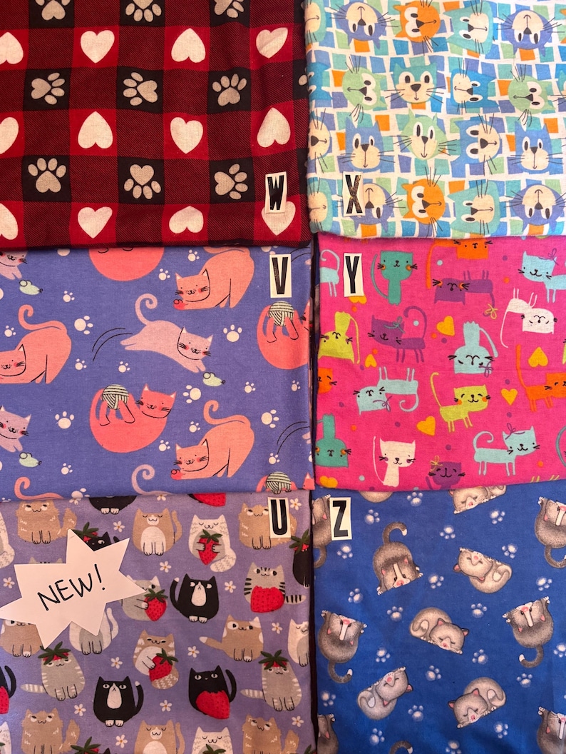 Op de afbeelding: Zes stoffen met verschillende kattenpatronen. Links boven een rood en zwart ruitpatroon met witte harten en pootafdrukken gelabeld W. Rechts boven een blauw en wit raster met kattengezichten gelabeld X. Midden links paars met roze katten gelabeld V. Midden rechts roze met kleurrijke katten gelabeld Y. Links onder lichtpaars met katten die aardbeien vasthouden gelabeld U en NEW. Rechts onder blauw met slapende katten gelabeld Z.