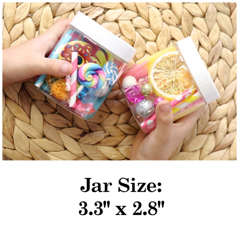 May include: Two clear glass jars with white lids filled with colorful items. The jar on the left contains colorful candies, straws, and pom poms. The jar on the right contains a dried lemon slice, straws, and pink and white polka dot paper. The text 'Jar Size: 3.3' x 2.8' is below the jars.