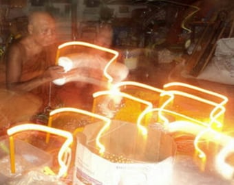May include: A person in a robe sits in a dimly lit room with glowing orange lights. The lights are arranged in a pattern of intersecting lines, creating a geometric design.