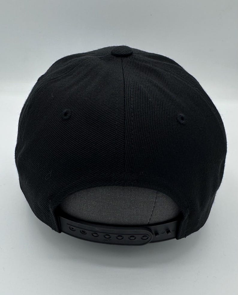 Puede incluir: Gorra de b&eacute;isbol negra con una correa ajustable negra y una parte inferior gris.