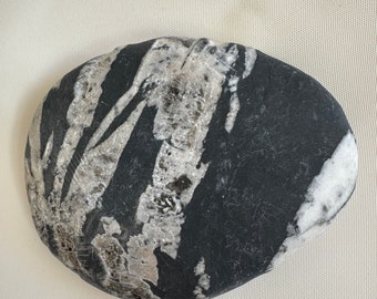 May include: A smooth, black and white stone with a unique, swirling pattern. The stone has a natural, polished finish.