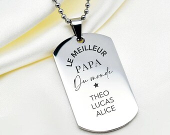 Puede incluir: Un colgante de placa de identificación de metal plateado en una cadena de bolas a juego. El colgante está grabado con el texto LE MEILLEUR PAPA Du monde, un pequeño símbolo de estrella y los nombres THEO, LUCAS y ALICE en letra oscura.