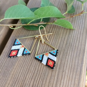 May include: A pair of gold triangle earrings with black, white, red, and turquoise beaded designs.