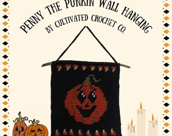 Può includere: Appeso a parete all'uncinetto nero con un design a zucca sorridente. Lo striscione recita "Penny the Punkin Wall Hanging by Cultivated Crochet Co." ed è decorato con caramelle di mais e un tassello di legno. Include illustrazioni di zucche e candele.