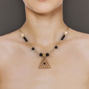 May include: A gold necklace with black and white beads and a geometric triangle pendant.
