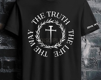 Puede incluir: Una camiseta negra de manga corta con un gráfico circular blanco en el pecho. El diseño incluye una cruz de clavo central rodeada por una corona de laurel y el texto THE WAY THE TRUTH THE LIFE. La manga muestra el texto JOHN 14:6.