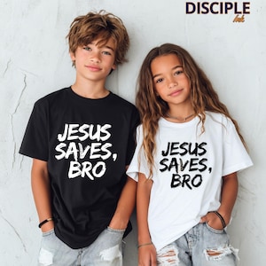 Op de afbeelding: Twee kinderen dragen bijpassende t-shirts. E&eacute;n zwart, &eacute;&eacute;n wit, beide met de tekst "JESUS SAVES, BRO" in een vetgedrukte, witte letter. Ze dragen lichtblauwe spijkerbroeken. De tekst "DISCIPLE ink" is zichtbaar.