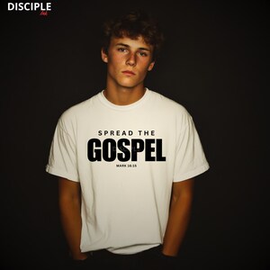 May include: A white short-sleeved t-shirt featuring the black text SPREAD THE GOSPEL and MARK 16:15 printed on the chest. The top left corner displays the text DISCIPLE Ink. The garment is presented against a dark, solid background.