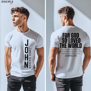 May include: White t-shirt with the text "JOHN THREE SIXTEEN" printed vertically on the front. The back of the shirt features the text "FOR GOD SO LOVED THE WORLD" and a Bible verse. The shirt is a crew neck style.