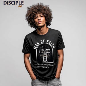 May include: Black t-shirt with the text "MAN OF FAITH" above a cross design with a lion's face. The text "PURSUE RIGHTEOUSNESS, GODLINESS, FAITH, LOVE, ENDURANCE AND GENTLENESS" is below the cross. The brand "DISCIPLE ink" is in the top left corner.