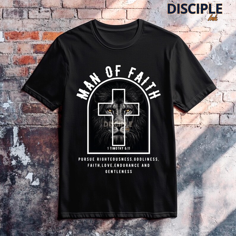 May include: Black t-shirt with a graphic featuring a lion's face within a cross, and the words "MAN OF FAITH." The text "1 Timothy 6:11" and a quote about righteousness, faith, and gentleness are also printed on the shirt.