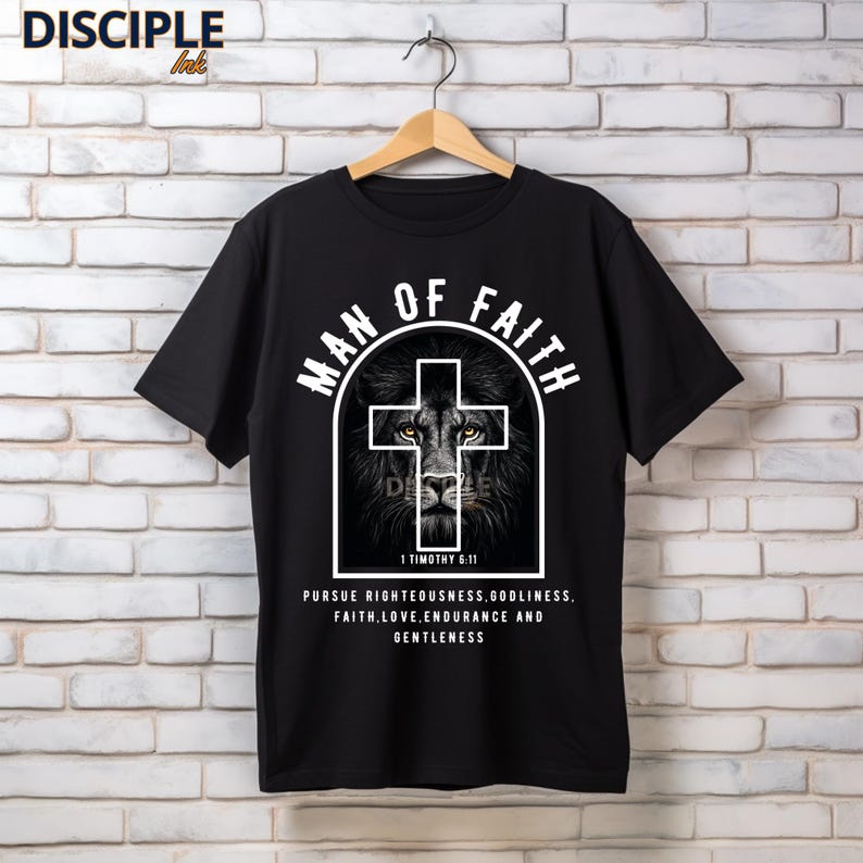 May include: Black t-shirt with the text "MAN OF FAITH" above a cross-shaped design featuring a lion's face. The shirt also includes the Bible verse 1 Timothy 6:11 and other text about faith.