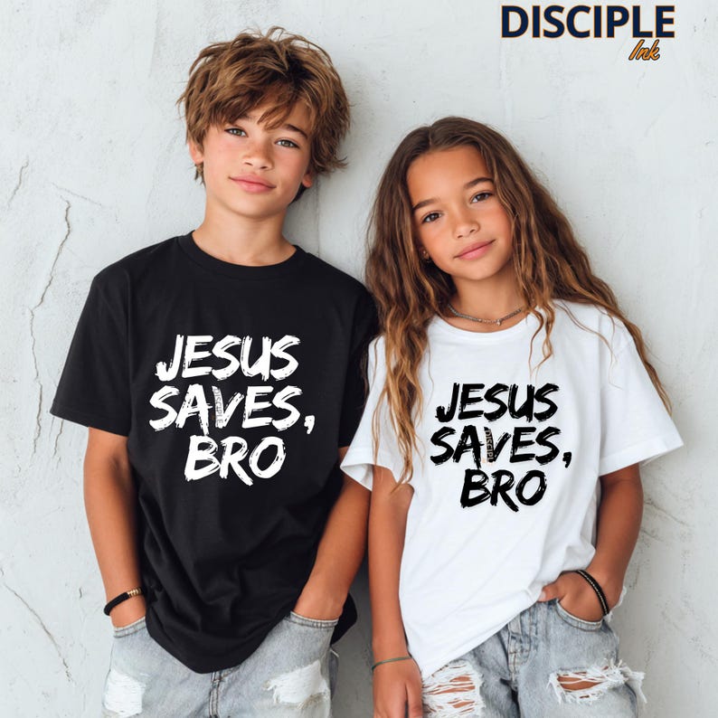 Op de afbeelding: Twee kinderen dragen bijpassende t-shirts. E&eacute;n zwart, &eacute;&eacute;n wit, beide met de tekst "JESUS SAVES, BRO" in een vetgedrukte, witte letter. Ze dragen lichtblauwe spijkerbroeken. De tekst "DISCIPLE ink" is zichtbaar.
