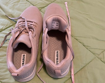 May include: A pair of light gray sneakers with white soles. The sneakers have a mesh upper and a lace-up closure. The brand name "UBARIS" is printed on the inside of the shoes.