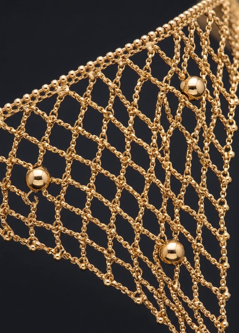 Puede incluir: Primer plano de un accesorio de estilo cota de malla de color dorado. El intrincado dise&ntilde;o presenta un patr&oacute;n en forma de diamante creado por cadenas interconectadas. Varias peque&ntilde;as cuentas redondas de color dorado se intercalan en el dise&ntilde;o, con cuentas esf&eacute;ricas m&aacute;s grandes a intervalos.