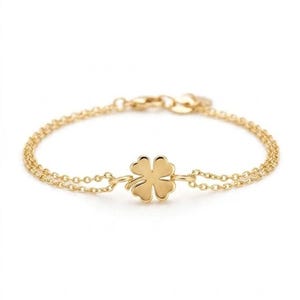 Könnte beinhalten: Ein goldfarbenes Armband mit einem zarten Doppelketten-Design. In der Mitte des Armbands befindet sich ein polierter vierblättriger Kleeblatt-Anhänger. Das Schmuckstück verfügt über einen kleinen runden Verschlussmechanismus an der Rückseite.
