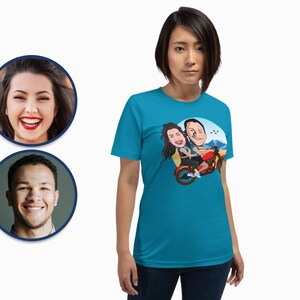Pode incluir: Uma camiseta turquesa com uma ilustra&ccedil;&atilde;o de desenho animado de um casal a andar de moto. O casal est&aacute; vestido com roupas casuais e a moto &eacute; vermelha. O fundo &eacute; um c&eacute;u azul com montanhas ao longe.