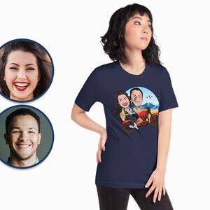 Pode incluir: Uma camiseta azul marinho com uma ilustra&ccedil;&atilde;o de desenho animado de um casal a andar de moto. A ilustra&ccedil;&atilde;o &eacute; sobre um fundo de c&eacute;u azul com montanhas.