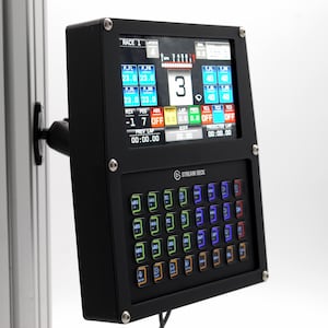 May include: A black Stream Deck device with a screen displaying racing data and a grid of colorful buttons. The screen shows numbers, indicators, and the text "RACE 1". The device is mounted on a metal pole.