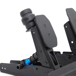 May include: Black racing pedals with a spring and blue accents. The pedals have a textured surface and are mounted on a black base. The design includes a cylindrical component and a logo.