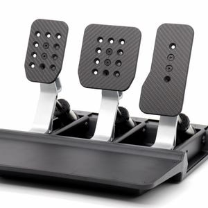 May include: A set of three racing simulator pedals featuring carbon fibre textured faceplates with circular cutouts, mounted on silver metal arms. The assembly is attached to a black base with a flat front plate and exposed mechanical components.
