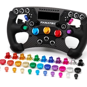 May include: A black carbon fibre Fanatec racing steering wheel with a central display, multiple buttons, and rotary encoders. Included are several sets of interchangeable, colourful metallic knobs in red, orange, yellow, green, blue, purple, pink, silver, and black.