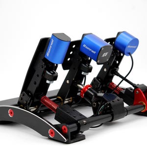 May include: A black and red racing simulator pedal set with three blue cylinders. The pedals have a spring and damper system. The cylinders have the Simnet logo. The base is black with red accents.