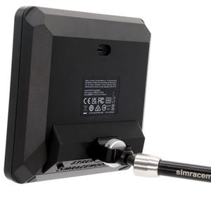 May include: A black rectangular electronic display screen mounted on an adjustable black and silver metal arm. The back of the device features a central port, a rectangular label with regulatory text, and the text SIMRACEMODS.COM on the arm.