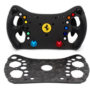 May include: A black carbon fiber racing steering wheel featuring a central yellow Ferrari logo, black rubberized grips, and an array of colorful buttons including red, orange, blue, and green. Below it lies a matching flat carbon fiber plate.