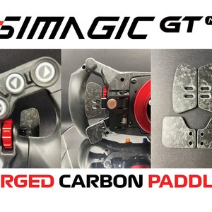 May include: SimAGIC GT NEO racing wheel with forged carbon fibre paddles. The paddles are black with a carbon fibre pattern and have red accents. The wheel is black with a red accent.