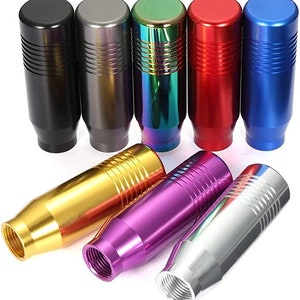 May include: Set of 10 different colored gear shift knobs. The knobs are made of aluminum and have a textured surface. The colors include black, silver, gold, purple, red, blue, green, and a rainbow iridescent color.