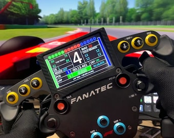 以下が含まれることがあります： レースデータを表示するデジタルディスプレイを備えた黒いレーシングステアリングホイール。ラップタイム、ポジション、タイヤ温度などが表示されます。ディスプレイには「FANATEC」というテキストも表示されています。
