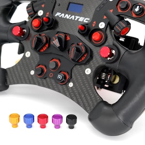 May include: A black racing steering wheel with a carbon fiber finish and red buttons. The steering wheel has a Fanatec logo and a variety of controls, including a knob, paddles, and buttons. The steering wheel is shown with five different colored replacement thumbsticks.
