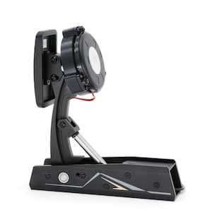 Pode incluir: Um pedal de bateria eletrónico preto com uma almofada circular e uma haste de metal prateada. O pedal tem uma base retangular com botões e um design decorativo. Um fio vermelho é visível.
