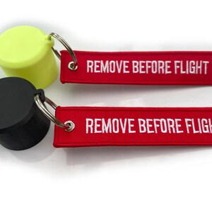 May include: Two black and yellow keychains with a silver ring and a red tag that says "REMOVE BEFORE FLIGHT".